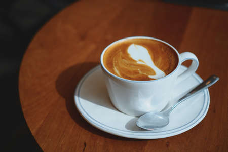 cup of coffee latte art on the wooden desk in coffee shop cafe with vintage color tone filter backgroundの写真素材
