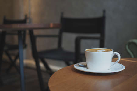 cup of coffee latte art on the wooden desk in coffee shop cafe with vintage color tone filter backgroundの写真素材