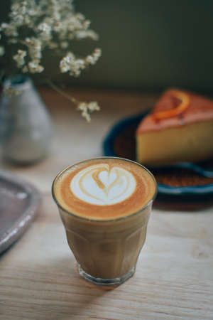 cup of coffee latte art on the wooden desk in coffee shop cafe with vintage color tone filter backgroundの写真素材