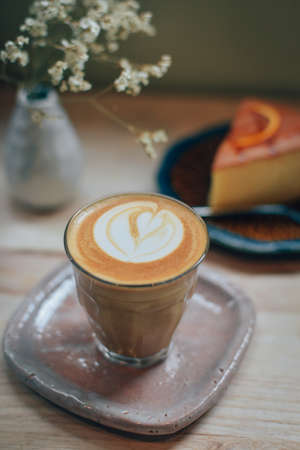 cup of coffee latte art on the wooden desk in coffee shop cafe with vintage color tone filter backgroundの写真素材