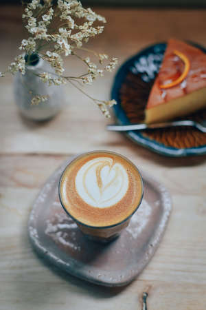 cup of coffee latte art on the wooden desk in coffee shop cafe with vintage color tone filter backgroundの写真素材