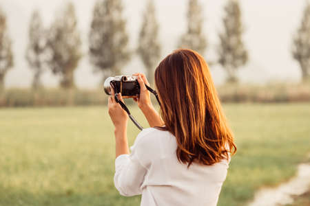 Beautiful Asian woman holding vintage camera in hand and standing over moutain background,traveler concept.の写真素材