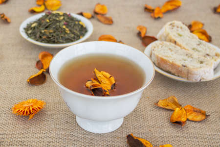 Herbal tea with grain bread and orange dried flowers on sackcloth background.の写真素材