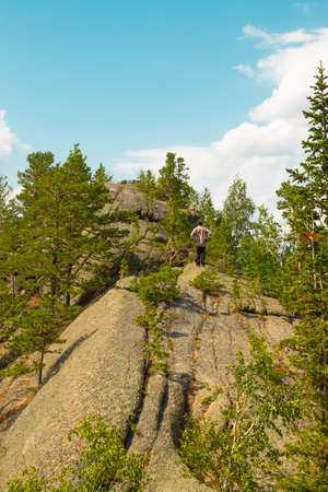Man standing on top of a mountain. Trees growing from stone. Altai region, Russia.の写真素材