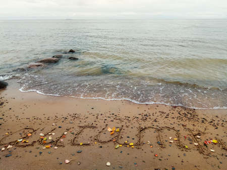 The inscription autumn on wet sand and autumn leaves on the Baltic Seaの写真素材