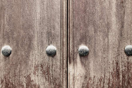 Old wood texture with natural patterns. Worn, weathered wooden gate with metal rivetsの写真素材