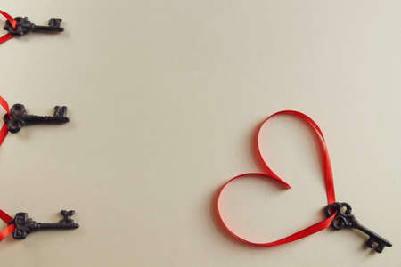 Heart with a red heart-shaped ribbon on a light background.の写真素材
