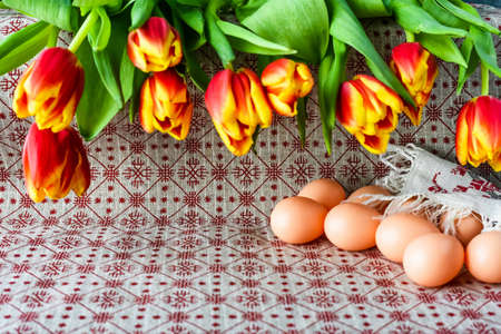 Easter eggs and fresh spring tulips on a tablecloth.の写真素材