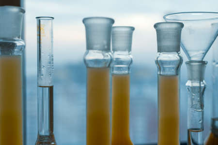 Closeup a long row of glass flasks with a yellow solution on a laboratory bench
