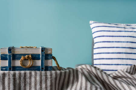 Marine style in the interior of the apartment - a sofa with pillows and the striped casket. Blue room marine concept.の写真素材
