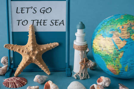 Globe, starfish, lighthouse and shells on a blue background with typography Lets go to the sea.