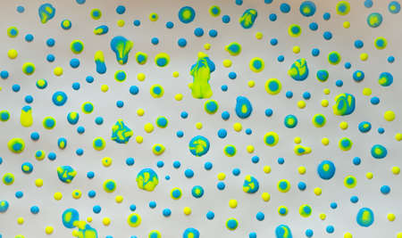 Yellow and blue drops of paint on white paper.