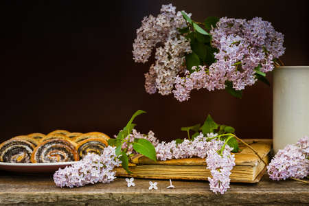 Muffins with poppy seeds and photo album, spring still life with a bouquet of lilacs on a wooden table.の写真素材