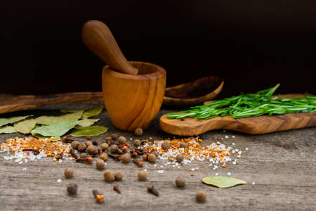 Spices and kitchen items made of olive wood on a rustic surface.