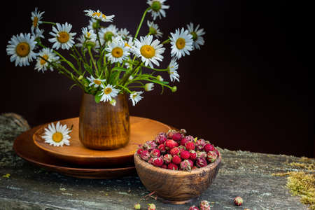 Sweet forest strawberries and a bouquet of daisies on a wooden background.の写真素材