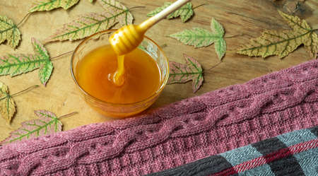 Autumn, warm clothes, maple leaves, berries and honey on a wooden surface.の写真素材
