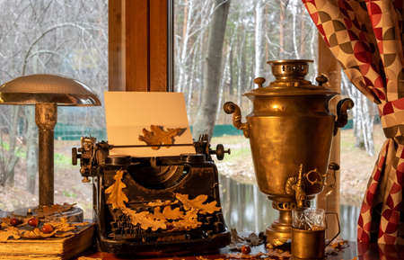 Vintage shabby typewriter, blank paper and fallen oak leaves in autumnの写真素材
