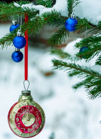 Retro clock Christmas toy on a Christmas tree in a winter forest