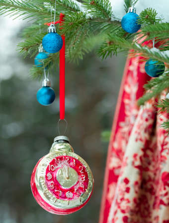 Retro clock Christmas toy on a Christmas tree in a winter forestの写真素材