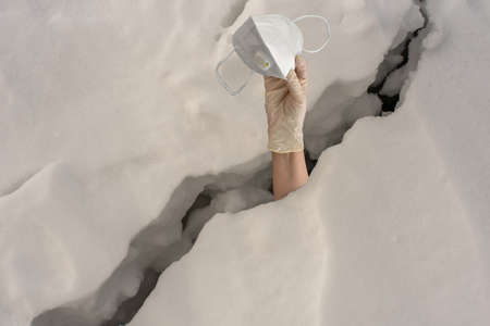 Hand in a glove with a medical mask pulls out of the crack