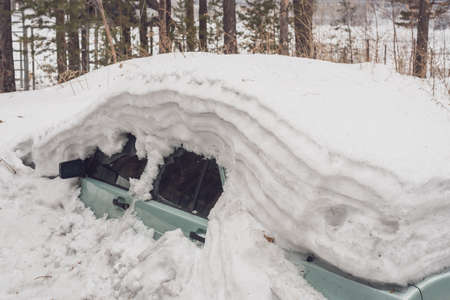 A passenger car, covered with snow, stood all winter in the street parkingの写真素材