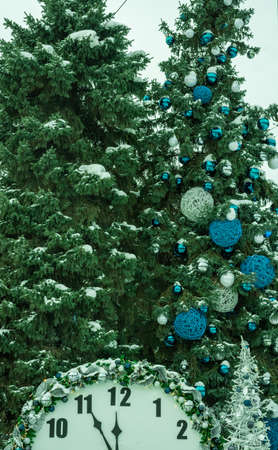 New Years Eve. Clock face and Christmas trees in the snow