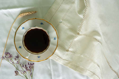 Cup of coffee on a white sheet. Coffee in bed. Flat lay