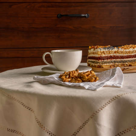 Breakfast at a table with a white tablecloth - a cup, sweet cake and walnuts