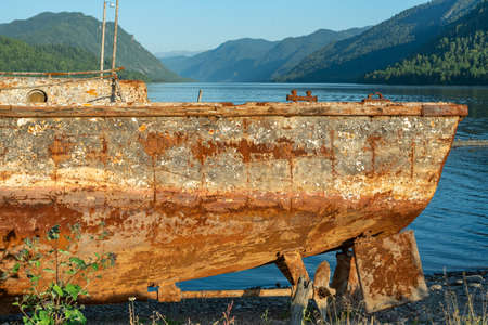 The abandoned old rusty ship placing on the coast of lake