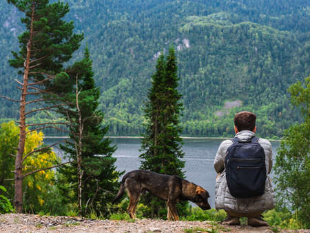 A man with a dog sitting by the lake and enjoying nature.の写真素材