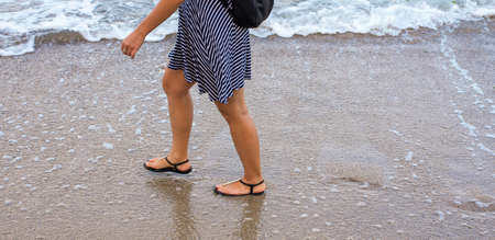 A girl walks along the wet sand along the seaの写真素材