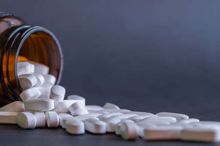White large tablets falling out of the bottle. Medicine and treatment concept.の写真素材