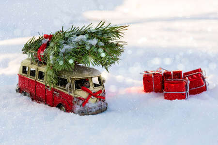 Red toy bus with a Christmas tree on the snowの写真素材