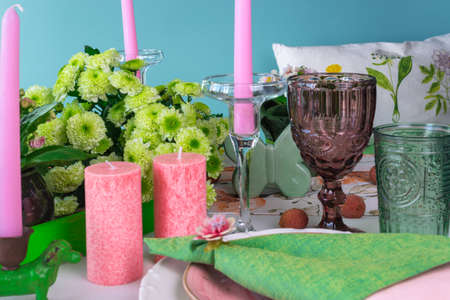 Romantic spring table setting for two with wine glasses, candles and flowers