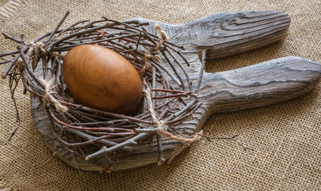 Easter composition - On the board with the ears of a rabbit lies a nest with an egg.の写真素材