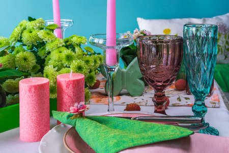 Spring table setting for two with wine glasses, candles and flowers.の写真素材
