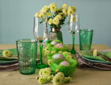 Set table with Easter decoration - eggs in nests and flowers.