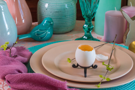 Spring table set for Easter - a chicken egg and a twig with the first leaves on a plate