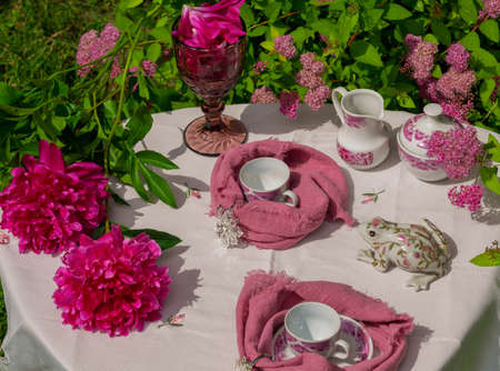 Morning tea on a table in the garden against the backdrop of a flowering shrub Japanese spireaの写真素材