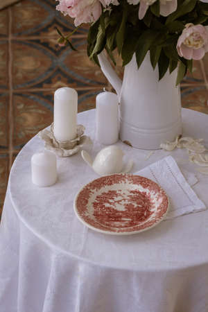 Table setting with a cup of tea and white peonies in a white ceramic jugの写真素材