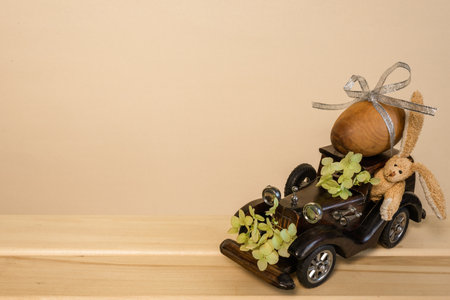 Easter. A brown wooden toy retro car carries an egg. Easter card with retro car and hareの写真素材