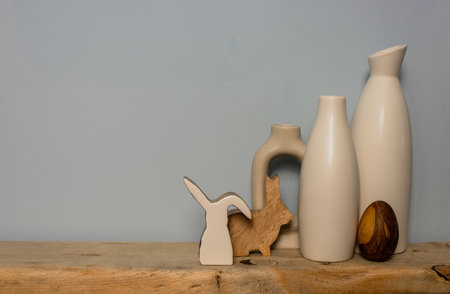 Rustic wooden decor white vases and an easter bunny figure on a wooden shelf. Copy space.の写真素材