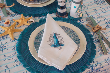 Napkin with an embroidered beacon on a plate. Blue color, marine style, table setting.の写真素材
