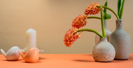 Pink hyacinths in white ceramic vases and figurines of birds against a beige wallの写真素材