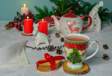 New Years tea party at the table with a teapot, candles, cookies and fir branchesの写真素材