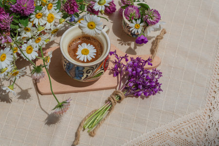 Coffee with foam and spring wildflowers on a white tablecloth.の写真素材
