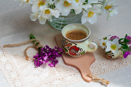 Coffee with foam and spring wildflowers on a white tablecloth.の写真素材