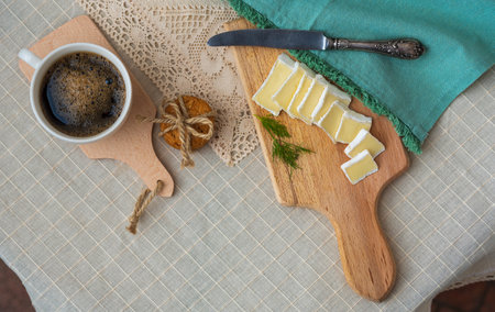 Breakfast - a cup of coffee, cookies and bru cheese on a cutting wooden board