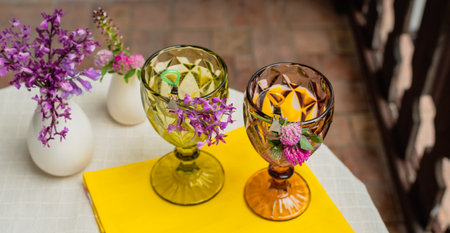 Glasses with a drink and flowers and flowers in a vase on a table with a white tablecloth.の写真素材
