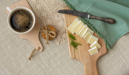 Breakfast - a cup of coffee, cookies and bru cheese on a cutting wooden boardの写真素材